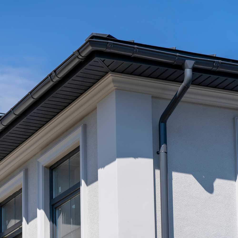 black-gutter-on-white-house Atlanta home with black seamless gutters installed by KTM Roofing in Atlanta, GA.
