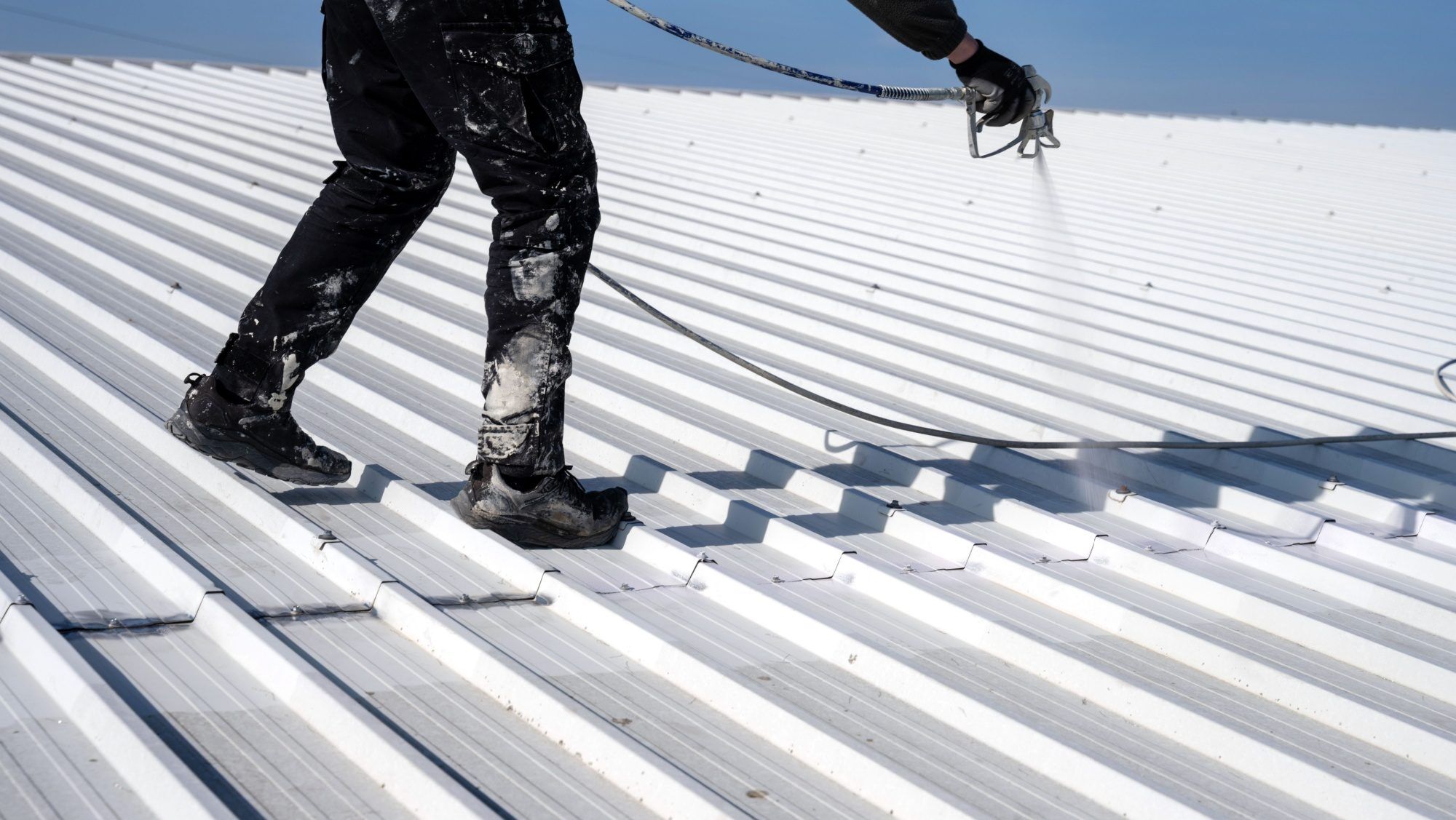 man coating a metal roof