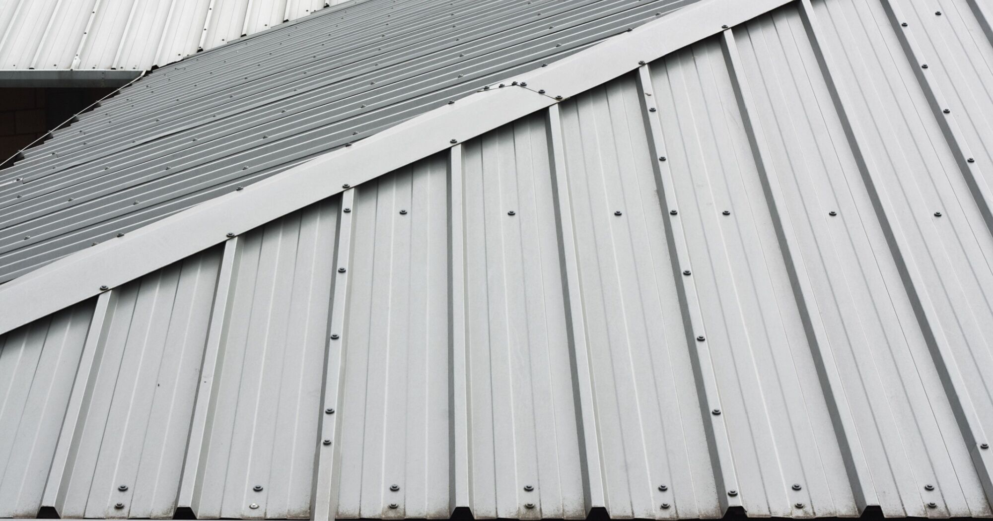 benefits-of-metal-roofing-for-commercial-buildings Close-up view of a metal roof with overlapping panels and fasteners, showcasing the durability and weather resistance of metal roofing for commercial buildings.