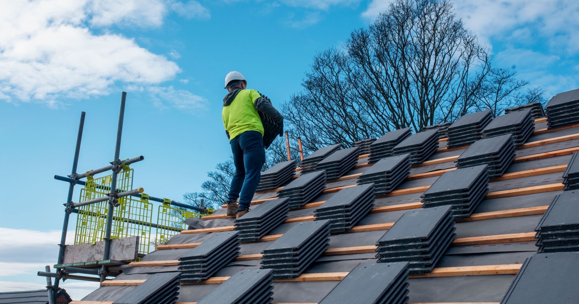 true-cost-of-a-new-roof A roofing contractor installing new shingles on a home.