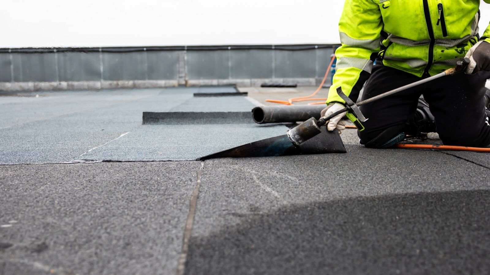 Commercial roofer applying roof coating for flat roof in Atlanta, GA.
